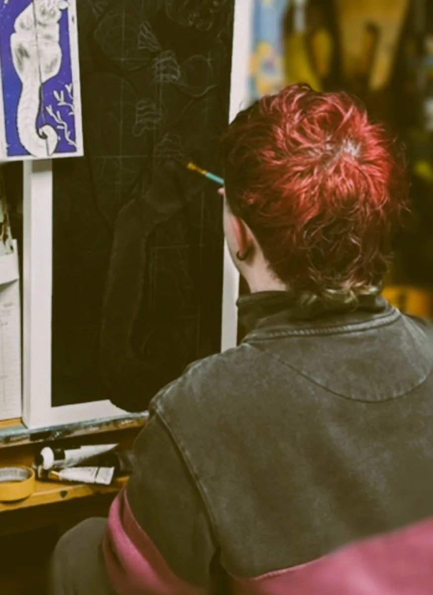 Silas painting at an easel in the studio, seen from behind